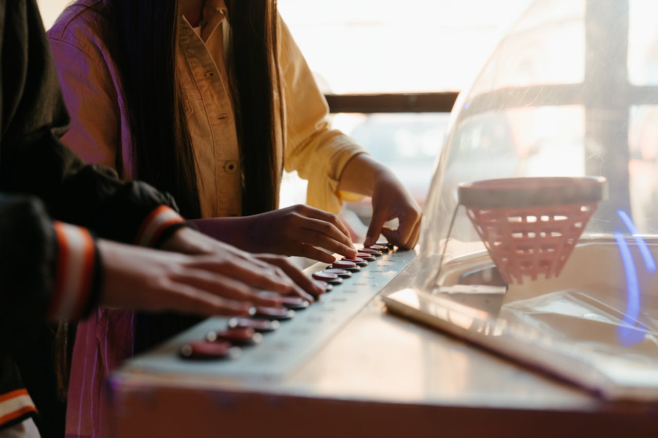 Close-up of teenagers enjoying a retro arcade game machine indoors.