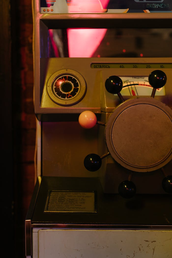 Close-up of a vintage gaming machine with a steering wheel in a dimly lit arcade.